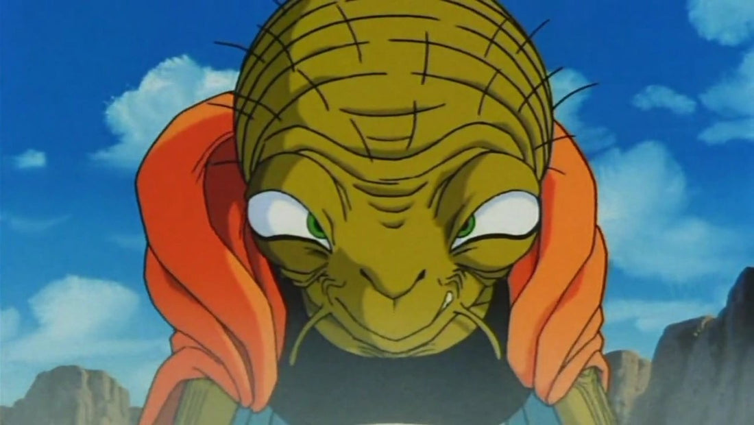 Babidi en gros plan, penché vers l'avant, visage ridé, yeux verts et cape orange, avec un sourire en coin sous un ciel bleu nuageux.