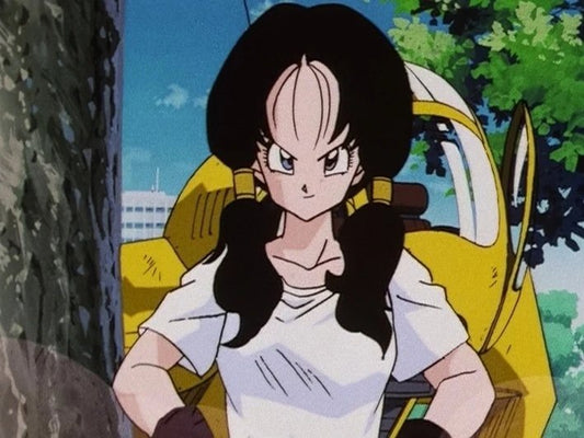 Videl, couettes noires et t-shirt blanc, poings sur les hanches et sourire en coin devant son appareil volant jaune, sous les arbres.